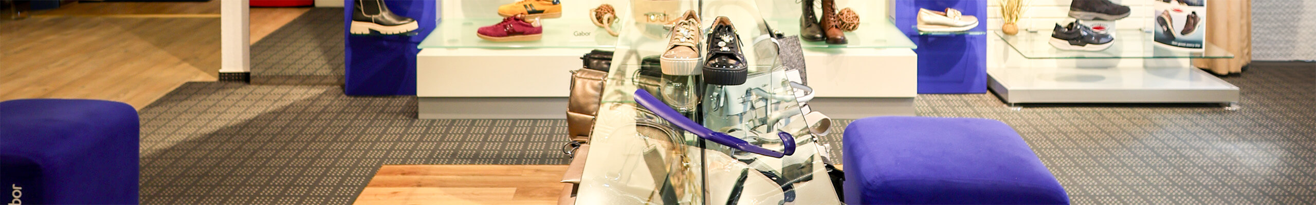 Ausgestellte Ware und blaue Hocker zum anprobieren der Schuhe.