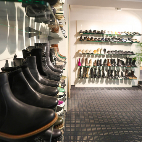 Eine Wand im Verkaufsraum mit vielen Damenschuhen und -stiefeln.