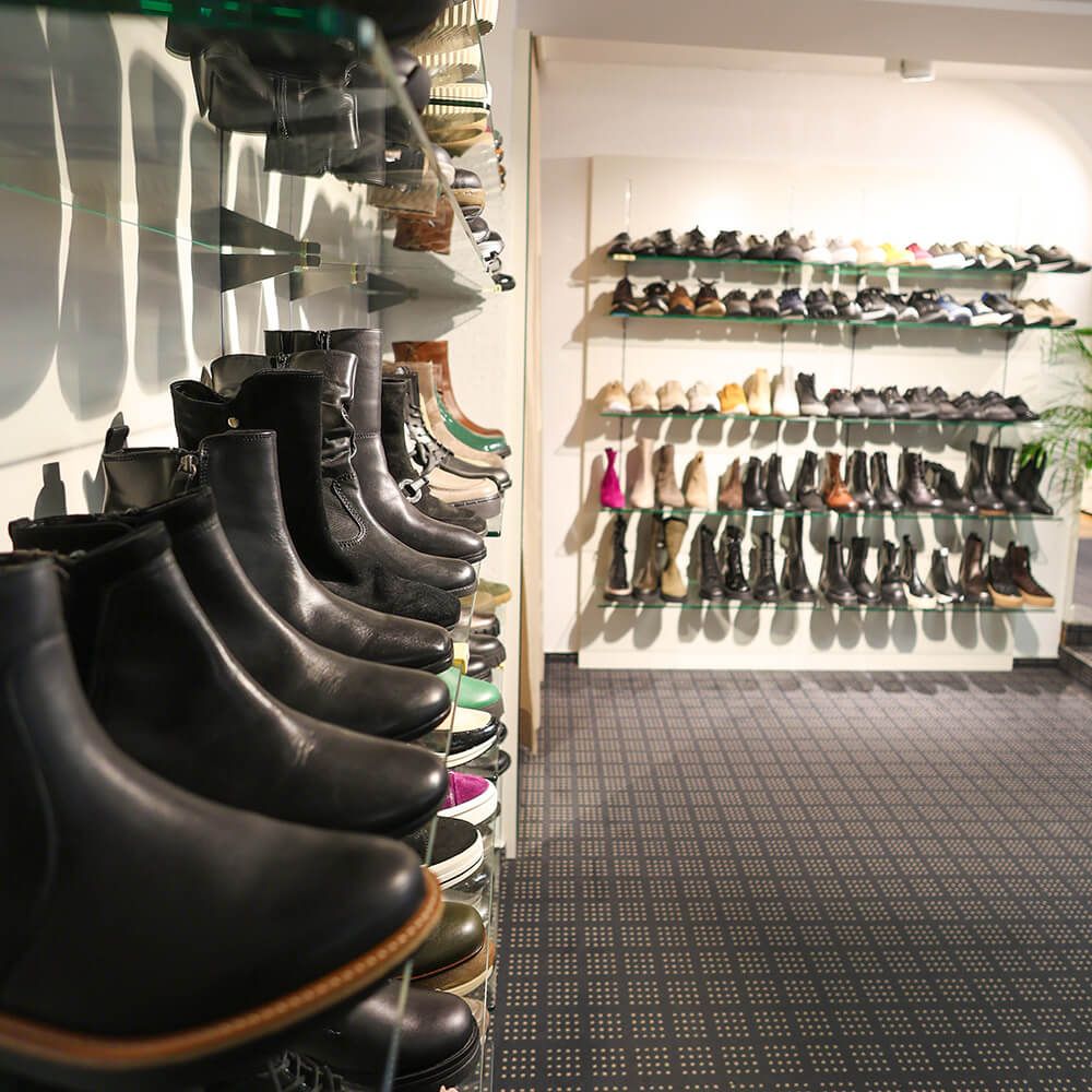 Eine Wand im Verkaufsraum mit vielen Damenschuhen und -stiefeln.